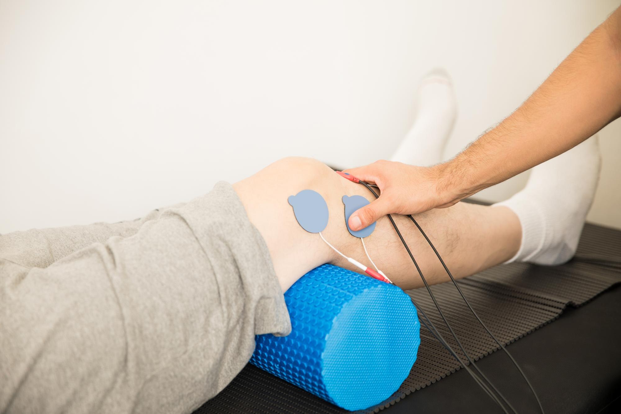 closeup-physiotherapist-s-hand-positioning-electrodes-patient-s-knee-hospital_662251-1760